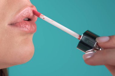 Dudaklarına kırmızı ruj süren bir kadın. Seksi kız ruj sürmüş. Kırmızı dudaklar makyaj malzemesi. Dudaklara ruj sürüyorum.
