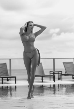 Yüzme havuzunda bikinili genç bir kadın, havuz başında seksi bir poz. Yaz tatili. Otelde havuz başında bikini mayo giymiş bronzlaşmış bir kız. Yaz turizmi