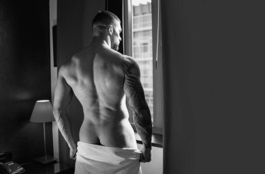 Man with naked body, muscular shoulders. Naked man in bed. Muscular sexy male body. Gay sexy model. Muscular sexy man with naked torso near window curtains. Hunk with athletic body. Guy enjoying night