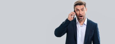 Takım elbiseli bir iş adamı telefonda konuşuyor. Promosyon mobil uygulaması. Stüdyonun arka planında izole edilmiş akıllı telefon kullanan sıradan giyinmiş bir iş adamı. Başlık için afiş, kopyalama alanı. Web tasarımı için poster