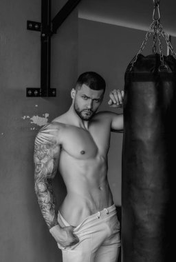 Seksi, çıplak, sportif vücut. Spor salonunda güçlü bir boksör. Spor kulübünde kum torbasıyla spor erkek antrenmanı. Genç adamın fitness antrenmanı var. Erkek sporcu spor yapar.