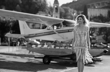 Beautiful model walks away from her private jet on holiday. Business woman near private jet. Luxury travel in Como lake Italy. Charter jet airplane. Sensual woman on the street near jet plane