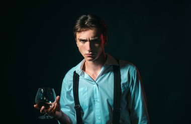 Klasik giyimli şık ve şık bir adam ve bilge bir adam. Bir bardak viski tutan şık, zengin bir genç adam.