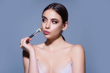 Beauty girl with makeup brushes. Make up for woman. Girl with makeup brushes near face. Cosmetic brush. Facial Makeup. Female model applying blush powder foundation tone