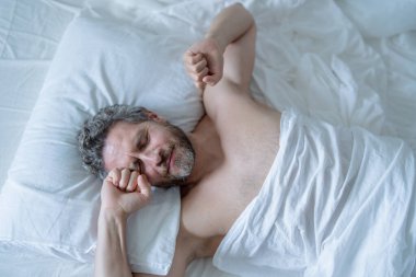 Yastıkta erkek kafası. Gri saçlı adam yatakta uyanıyor. Son sınıf öğrencisi yatak odasında uyanıyor. Olgun bir adam sabah evde uyanıyor. İyi uykular. Milenyum adamı yatakta uyanıyor. İnsanlar yatma vakti