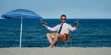 İş tatili. Yaz tatilinde yakışıklı bir iş adamı. İş adamı elinde dizüstü bilgisayarla deniz sahilinde dinleniyor. Yaz işi. Yaz Denizi Sahili 'nde serbest yazar. Yaz haftasonu ve uzak bağımsız çalışma