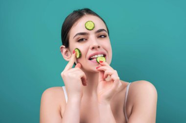 Woman with facial mask with slices of fresh cucumber on face. Cosmetic procedure. Beauty spa and cosmetology. Spa woman applying facial clay mask. Beauty treatments