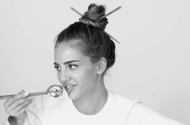 Suşi yiyen güzel seksi kadın. Suşi rulo, sashimi. Manken kız yemek çubuklarıyla suşi yiyor. Yemek çubuklarıyla saç kesimi, sağlıklı Japon yemekleri yemek.