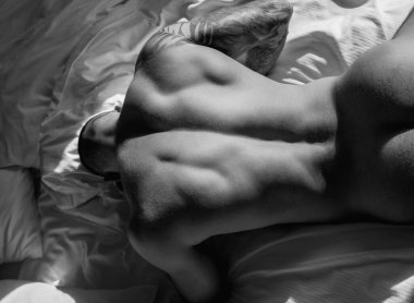 Closeup sexy male round buttocks, Sexy shape butt. Sexy and naked muscular young man posing on the sofa. Sexy shirtless male model lying in bed