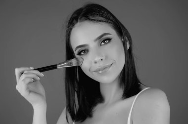 Beauty girl with makeup brushes. Make up for woman. Girl with makeup brushes near face. Cosmetic brush. Facial Makeup. Female model applying blush powder foundation tone