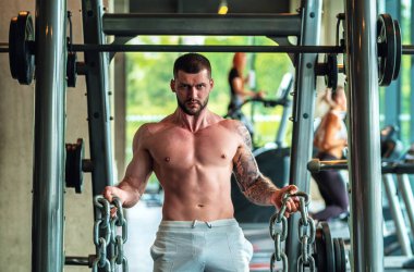 Handsome fit muscular caucasian man workout in the gym with weight pumping up muscles. Fitness and bodybuilding sport. Bodybuilder with dumbbells at gym, hard workout