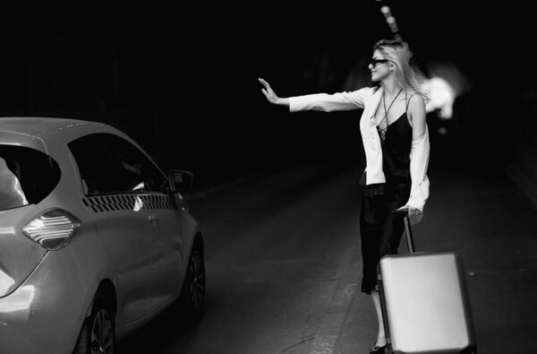 Женщина с чемоданом берёт такси. Туристка с дорожной сумкой путешествует. Путешествие по Европе по выходным