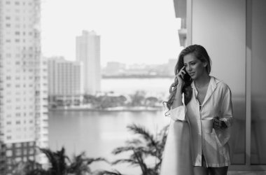 Girl using phone device gadget app isolated on balcony terrace. Woman holding a smartphone, chatting by mobile phone. Girl using phone, studio portrait. Woman makes telephone call on phone