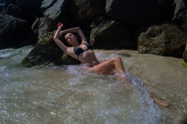 Plaj tatilinde bronzlaşmış seksi ince bikini modeli. Denizde bikinili bir kız. Bikinili seksi bir kadın vücudu. Tropik plajda yaz tatili. Yaz iç çamaşırı bikini.