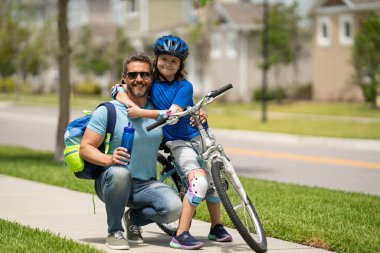 Baba oğul kavramı. Baba oğluna bisiklet sürmeyi öğretiyor. Baba oğlunun Amerikan mahallesinde bisiklet sürmesine yardım ediyor. Sevgi dolu bir aile. Baba oğul kucaklaşması. Babalar Günü