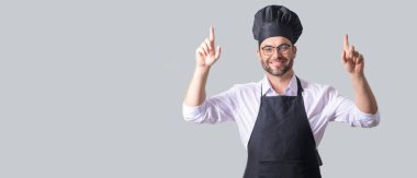 Siyah önlüklü bir erkek tencere. Şef şapkalı adam. İnsan yemeklerinin ayrı bir portresi.