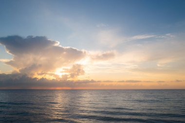 Deniz batımında bulutlu gökyüzü, okyanus sahilinde gün doğumu. Gün batımından sonra gökyüzünde gün batımı manzarası. Gökyüzüne ve denize karşı farklı renkte bulutlarla gün doğumu