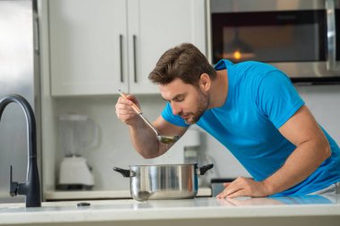 Aşçı mutfakta yemek pişiriyor. Şef aşçı tencereli bir yemek hazırlıyor. Menü tarifi sağlıklı yemek. Şef modern mutfakta yemek pişiriyor. Olgun aşçı mutfakta yemek hazırlıyor.