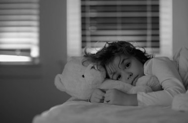 Yatağında rahat, yumuşak yastıklı, beyaz çarşaflı, uykulu bir çocuk. Çocuk battaniyeyi örtüyor. İyi geceler. Çocukluk kavramı