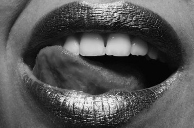 Dişi dolgun dudakları altınla kapat. Altın parıltılı ruj. Seksi dudak için parlak bir tarz. Şehvetli kadın dudakları. Şatafatlı altın ağız. Parlak altın dudaklar. Altın boyalı altın dudaklar veya metalik ruj