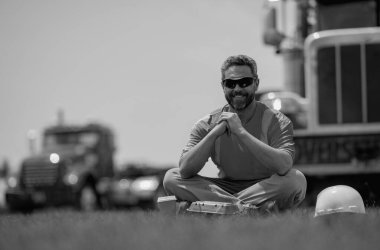 İşçi mola veriyor. İnşaatçı kahve içip dinleniyor. İnşaat işçisi işten sonra kahve molasında dinlendi. İşçi öğle yemeği yiyor. Mühendis dinleniyor ve inşaat alanı ve kamyonların yanındaki öğle yemeğinde dinleniyor.