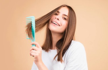 Genç ve güzel bir kadın kahverengi saçlarını tarıyor. Saç Bakımı. Saç fırçasıyla saç tarayan güzel esmer kadın. Tarak ile sağlıklı saç fırçalamak