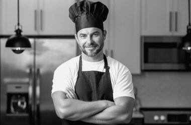 Yemek pişirme ve aşçılık konsepti. Mutfakta üniformalı aşçı. Erkek aşçı ya da önlüklü aşçı. Aşçının bereli portresi. Yemek pişirme konsepti