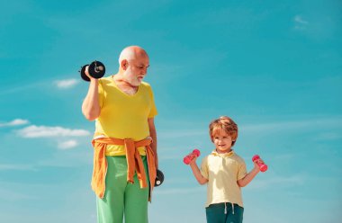 Aile sağlık kulübünde kıdemli adam ve çocuk. Sağlıklı bir yaşam tarzı. Ellerinde dambıllar olan büyükbaba ve torun. Küçük çocuklar için spor