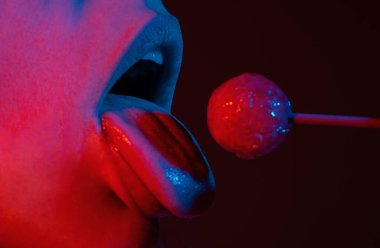 Close up lips with lollipop isolated, sexy blowjob, sensual mouth with lipstick eats sweets. Sexy design for women and girls. Beauty lips on neon lights. Night club background