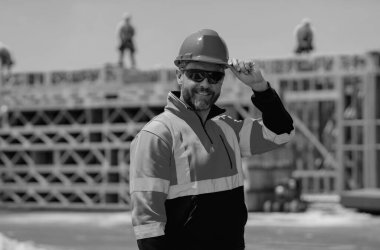 İnşaat işçisi inşaat halinde. İnşaat geçmişinde inşaat üniforması var. İnşaat alanındaki inşaatçı. Kasklı Amerikalı işçi. Bilder in hardhat