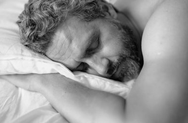 Yatağa git. Yaklaş. Erkek model beyaz yatakta uyuyor. Seksi üstsüz adam yatak odasında uyuyor. Latin kökenli olgun bir adam sabahları evde uyuyor. İyi uykular, uyku vakti. Yatakta uyuyan adam.