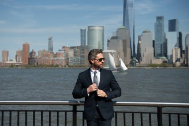 Kendine güvenen zengin iş adamı yöneticisi New York 'ta duruyor. İş dünyası Amerikan başarısı. Amerikan iş rüyası. Manhattan yakınlarında takım elbiseli Amerikalı işadamları. ABD 'de başarılı bir iş