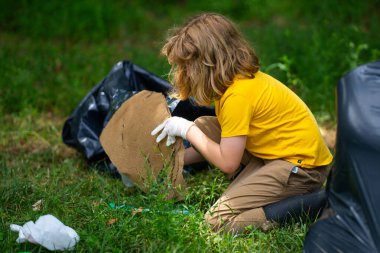 Küresel çevre kirliliği. Çocuk dışarıda plastik çöp topluyor. Çevre koruma kavramı. Çocuk çöp torbasına atık koyuyor. Eko çocuklar gönüllü. Çevre kirliliği