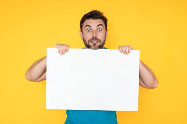 Stüdyonun arka planında tanıtım panosu gösteren hayret verici bir adam. Kopyalama uzayı olan boş tabela. Reklam konsepti. Fotokopi alanı olan reklam panosu, boş model. Boş tabela, pano