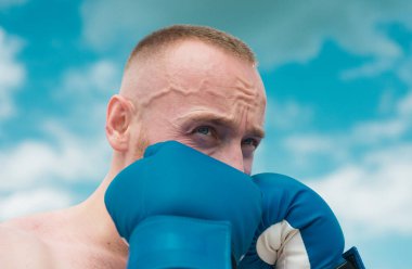 Boksör dövüşçüsü dışarıda antrenman yapıyor. Sporcu Muay Thai boksörü eldivenlerle dövüşüyor. Boks egzersizleri sırasındaki sporcu adam. Adam boks yaparken yüzünü kapatıyor.