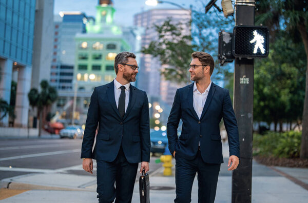 Business people discuss a project. Two young businessmen outdoors city looking cityscape. Businessmen communicating at meeting. Meeting of two business partners. Businessman in suits outdoors