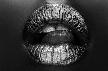 Seksi dilli. Şehvetli yalama. Altın dudaklar, seksi dudaklarda altın ruj, metalik ağız. Güzel kadın makyajı. Yakın çekim.