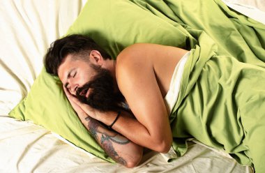 Yatakta uyumaya çalışan genç bir adam. Yakışıklı adam yatak odasında uyuyor, yatakta yatıyor. Dinlenmem gerek.