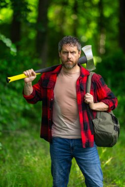 Kendine güvenen oduncu yaz ormanlarında çalışıyor. Baltalı adam. Ormanda ekose gömlekli bir oduncu. Baltalı hippi. Baltalı oduncu. Sakallı oduncu. Baltalı Amerikalı oduncu.