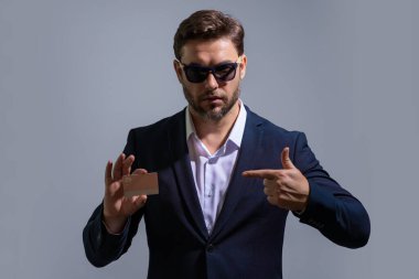 Stüdyonun gri arka planında kredi kartı tutan bir iş adamı. Kredi kartı olan adam, banka indirimi öneriyor. E-bankacılık, e-ticaret, para transferi için kredi kartı