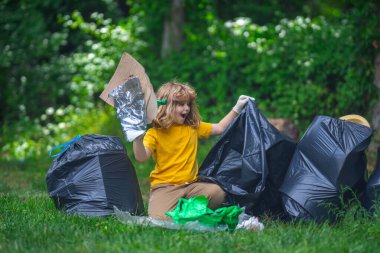 Lastik eldivenli çocuk çöp torbasıyla ormandaki çöpleri temizliyor. Eko, çevre koruma. Kirliliği geri dönüştür. Çocuk çöp ve plastik çöp topluyor. Ortamı kaydet