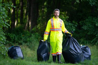 Çevre plastik kirliliği. Ormanda çöp toplayan ve elinde çöp torbası tutan bir gönüllü. Çevresel koruma. Çevre aktivisti. Çevre koruma ve atık kirliliği