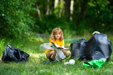 Küresel çevre kirliliği. Çocuk dışarıda plastik çöp topluyor. Çevre koruma kavramı. Çocuk çöp torbasına atık koyuyor. Eko çocuklar gönüllü. Çevre kirliliği