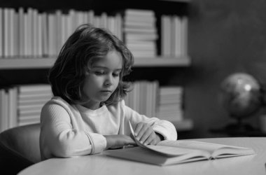 İlkokul çocuğu. Okul kütüphanesindeki küçük öğrenci. Okulda çocuk kitapları okuyor. Okulda okuyan inek bir öğrenci. Zeki, zeki okul çocuğu çok çalışıyor. Akıllı çocuk kitap okumayı öğreniyor.