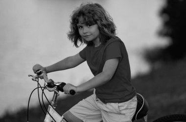 Bisikletli çocuk. Bisiklet süren kasklı bir çocuk. Şehir parkında bisiklet süren kasklı beyaz çocuk. Önce çocuk bisikleti. Çocuk yaz etkinliklerinde. Bisikletli çocuk. Çocuk bisiklete biniyor