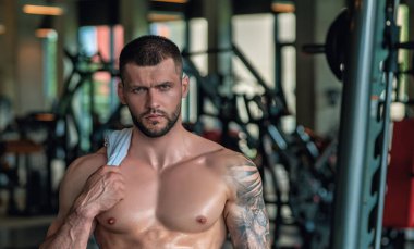 Ağırlık kaldıran kaslı vücutlu yakışıklı bir adamın portresi. Spor salonundaki adam. Spor eğitmeni, spor eğitmeni, sporcu, formda model, sporcu antrenmanı. Güçlü atletik vücut geliştirici.