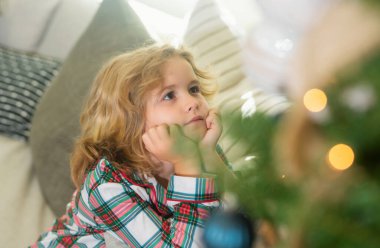 Mutlu çocuk evde Noel ağacının yanında. Kapalı portre, komik çocuk yüzü.