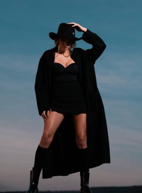 Siyah paltolu, şapkalı ve siyah çizmeli moda kadını. Dışarıdaki moda elbiseli kadın manken.