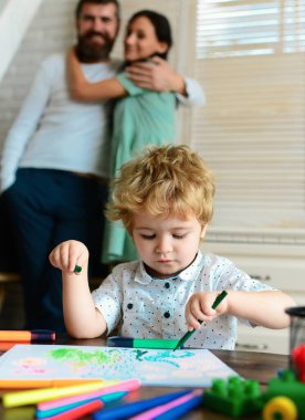 Evde çizim yapan anne ve babası olan bir çocuk. Aile tatili ve birliktelik. Anne, baba ve çocuk, tatil ve birliktelik. Erken dönem sanat ve zanaat eğitimi, çizim