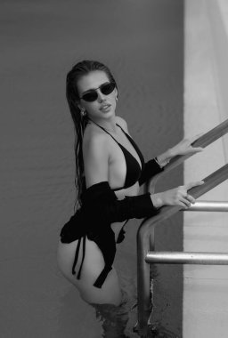 Sexy woman relaxing in swimming pool on summer vacation. Sexy sensual model in bikini. Resting, leisure and recreation, summer fun. Fashion woman in swimming pool. Glamour girl in luxury pool